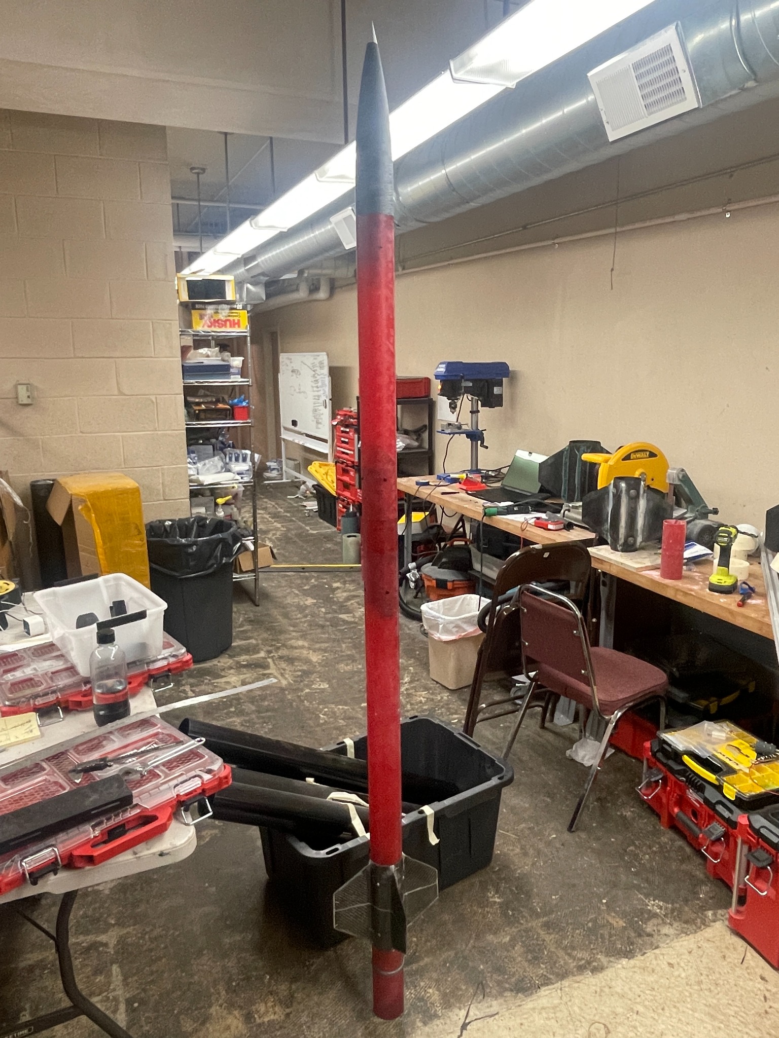 Tall red and black high-powered rocket in workshop